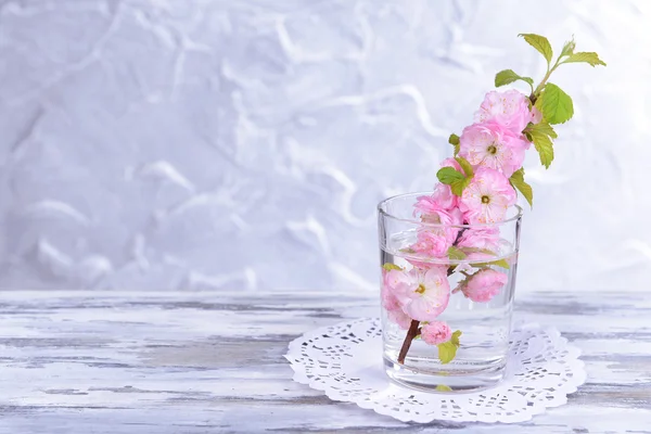 Hermosa flor de fruta en vidrio sobre mesa sobre fondo gris — Foto de Stock