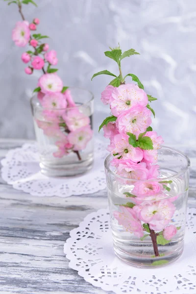 Beautiful fruit blossom in glass on table on grey background — Stock Photo, Image