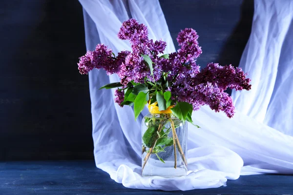 Beautiful lilac flowers in vase, on color wooden background — Stock Photo, Image