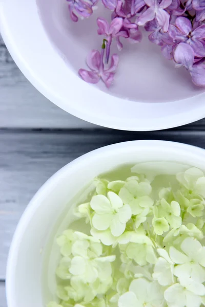 Cuencos de tratamiento de aromaterapia con flores y agua perfumada sobre fondo de madera —  Fotos de Stock