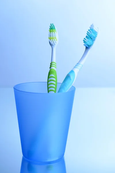 Cepillos de dientes en vidrio sobre fondo gris claro —  Fotos de Stock