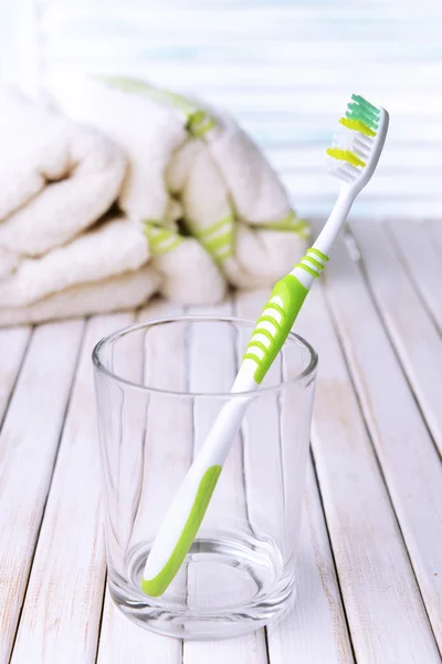 Cepillo de dientes en vidrio sobre mesa sobre fondo claro —  Fotos de Stock