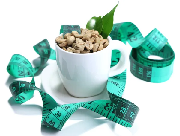 Raw green coffee beans in cup and measuring tape, isolated on white. Concept of weight loss — Stock Photo, Image