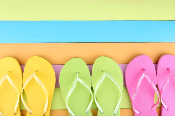 Bright flip-flops on color wooden background — Stock Photo, Image