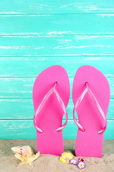 Bright flip-flops on sand, on wooden background — Stock Photo, Image