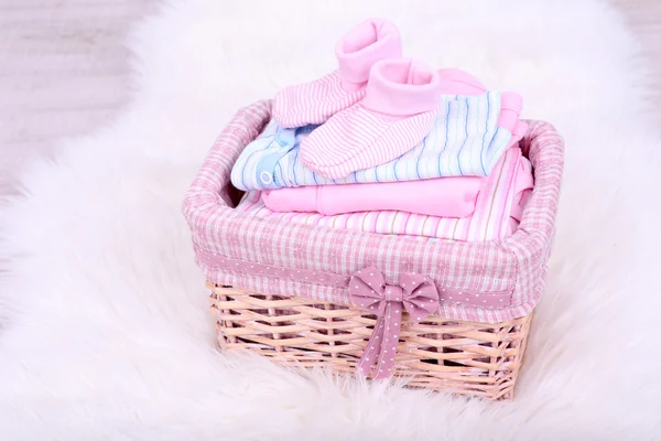 Baby clothes in basket on floor in room — Stock Photo, Image