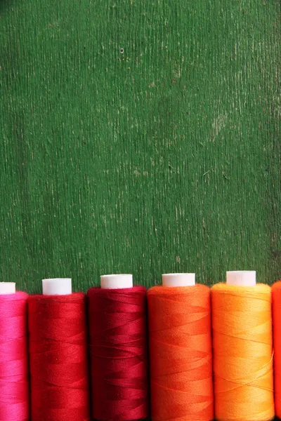 Multicolor sewing threads on wooden background — Stock Photo, Image