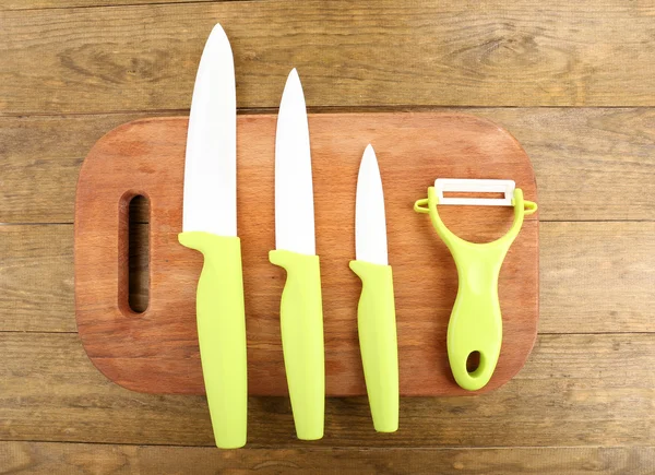 Cuchillos de cocina y tabla de cortar sobre mesa de madera — Foto de Stock