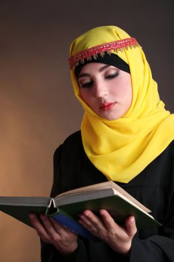 güzel Müslüman Arap kadın koyu renk arka plan üzerinde kitap okuma