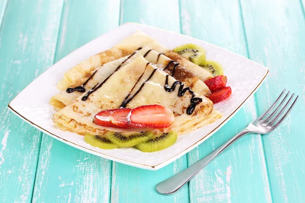 Delicious pancakes with strawberries and chocolate on plate on table — Stock Photo, Image