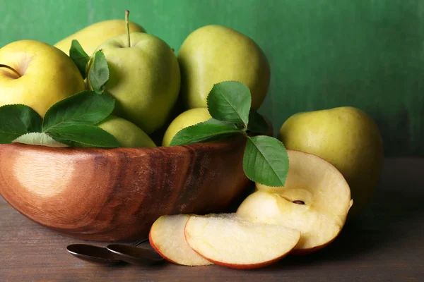 Manzanas dulces maduras con hojas en cuenco sobre fondo de madera — Foto de Stock