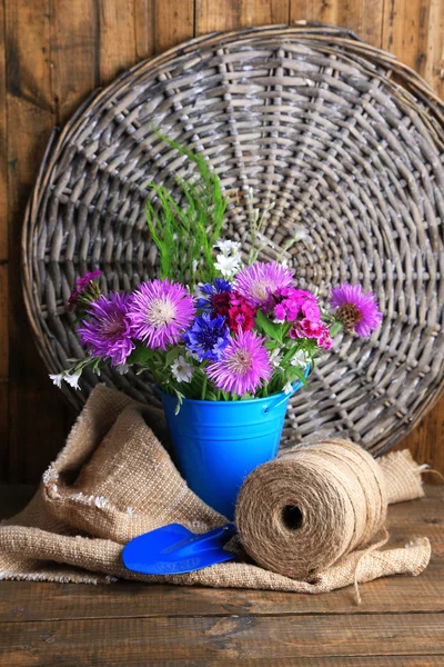 Jasne kwiaty w wiaderko na drewniane tła — Zdjęcie stockowe