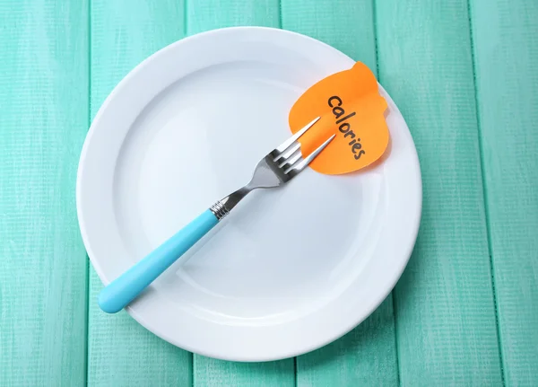 Note paper with message  attached to fork, on plate, on color wooden background — Stock Photo, Image