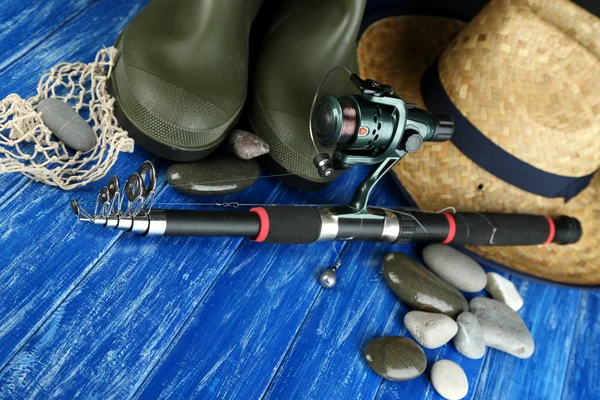Haste de pesca, gumboots e chapéu em mesa de madeira close-up — Fotografia de Stock