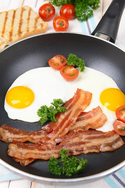 Ovos mexidos e bacon na frigideira em close-up de mesa — Fotografia de Stock