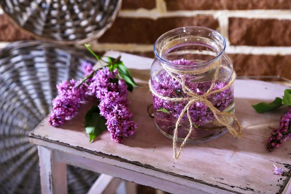 Lindas flores lilás em vaso, na escada de madeira, no fundo da parede de cor — Fotografia de Stock