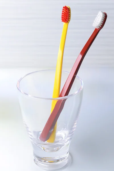 Zahnbürsten im Glas auf Tisch auf hellem Hintergrund — Stockfoto