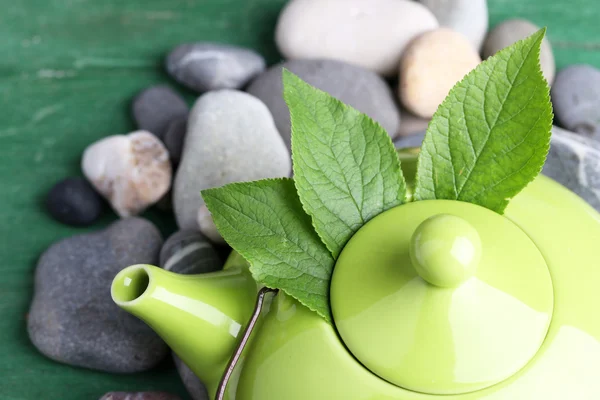 Teapot with dry flowers and herbs ingredients for tea, on stones and color wooden background — Stock Photo, Image