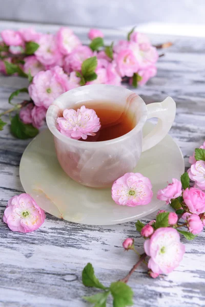 Красиві плоди цвітуть з чашкою чаю на столі крупним планом — стокове фото