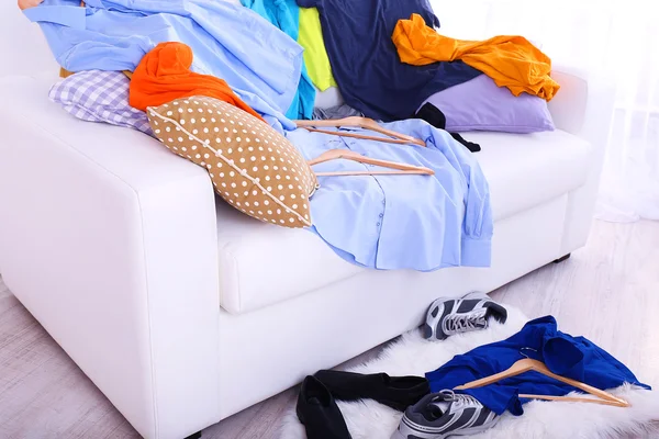 Chaotisch bunte Männerkleidung auf Sofa auf hellem Hintergrund — Stockfoto