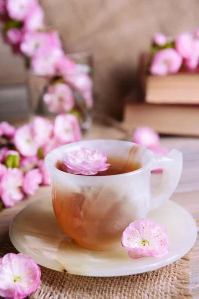 Beautiful fruit blossom with cup of tea on table on grey background