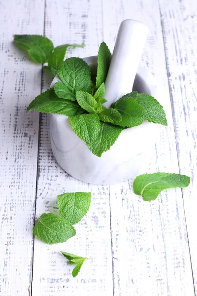 Menta verde fresca en mortero sobre fondo de madera de color — Foto de Stock