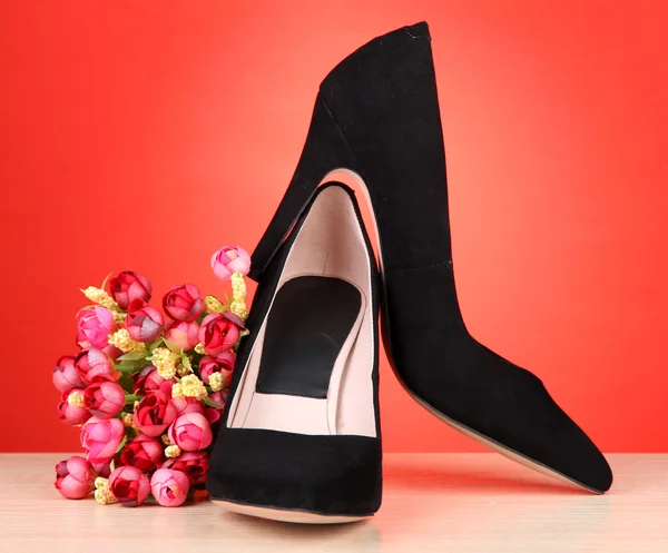 Mooie zwarte vrouwelijke schoenen en bloemen — Stockfoto