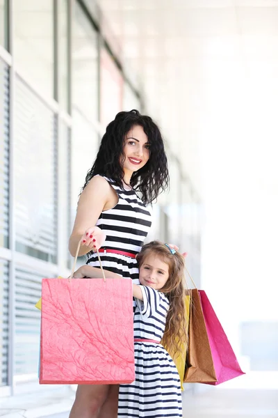 Mãe feliz e filha com sacos de loja, ao ar livre — Fotografia de Stock