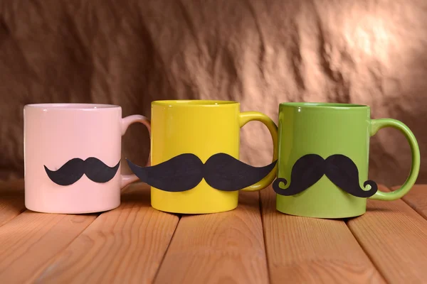 Tasses avec moustache sur la table sur fond brun — Photo