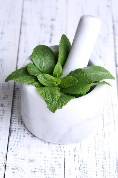 Fresh green mint in mortar on color wooden background — Stock Photo, Image