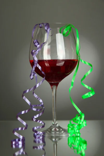 Glas rode wijn en streamer afterparty op grijze achtergrond — Stockfoto