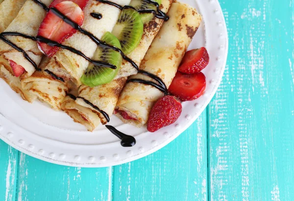 Leckere Pfannkuchen mit Erdbeeren und Schokolade auf dem Teller auf dem Tisch — Stockfoto