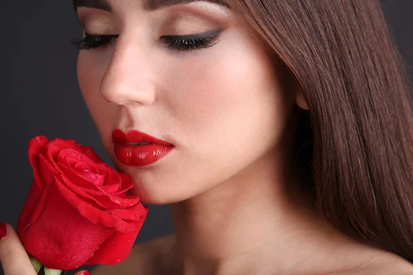 Mädchen mit roten Lippen und Rose auf dunklem Hintergrund — Stockfoto