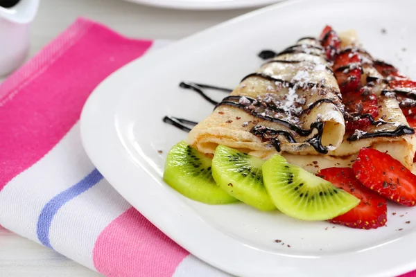 Deliciosas panquecas com morangos e chocolate no prato na mesa — Fotografia de Stock