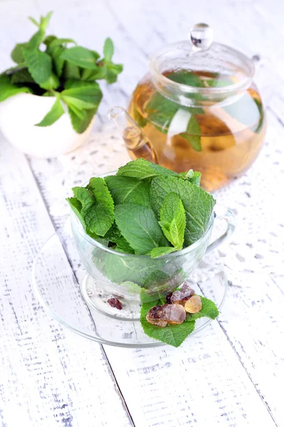 Mint leaves in glass cup on color wooden background — Stock Photo, Image