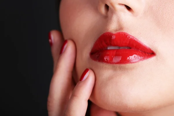 Flicka med röda läppar och naglar på mörk bakgrund — Stockfoto