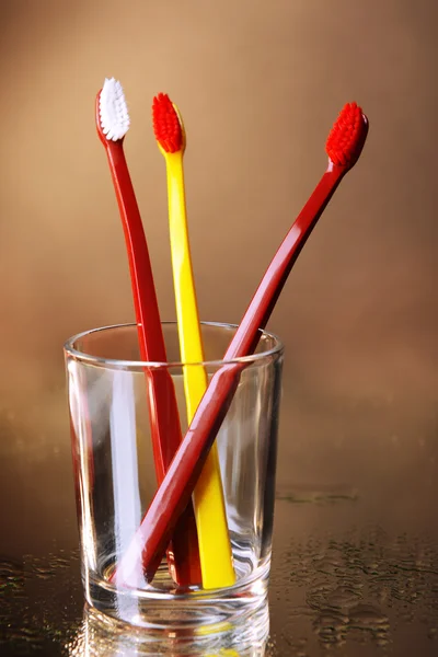 茶色の背景にガラスの歯ブラシ — ストック写真