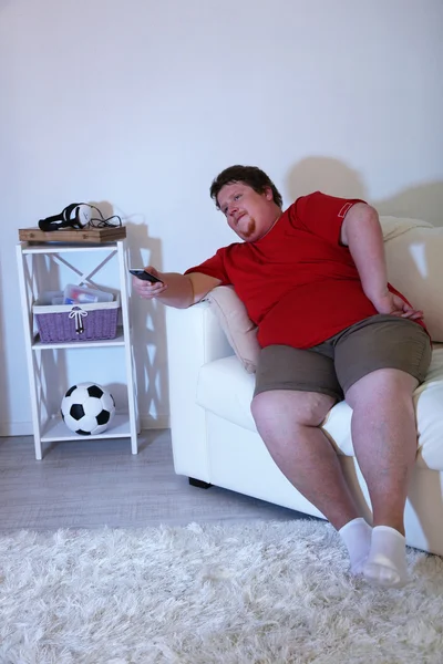 Lazy overweight male sitting on couch and watching television — Stock Photo, Image