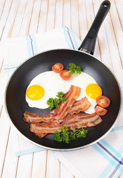 Scrambled eggs and bacon on frying pan on table close-up — Stock Photo, Image