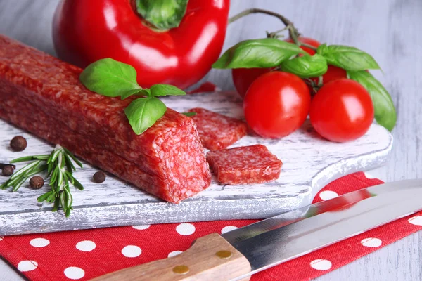 Savoureux salami saucisse, légumes, couteau et épices sur fond de bois — Photo