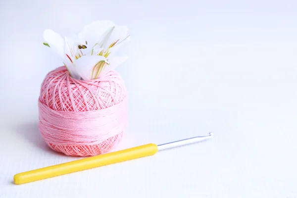 Colorful clew, crochet hook and fresh flower on light background — Stock Photo, Image