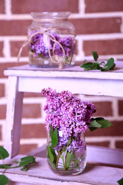 Mooie lila bloemen in vazen, op houten ladder, op een muur achtergrond kleur — Stockfoto