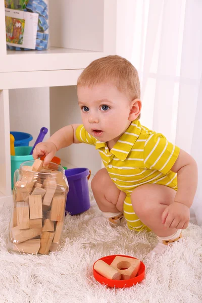Cute little boy with wooden toy blocks in room — Stock Photo, Image