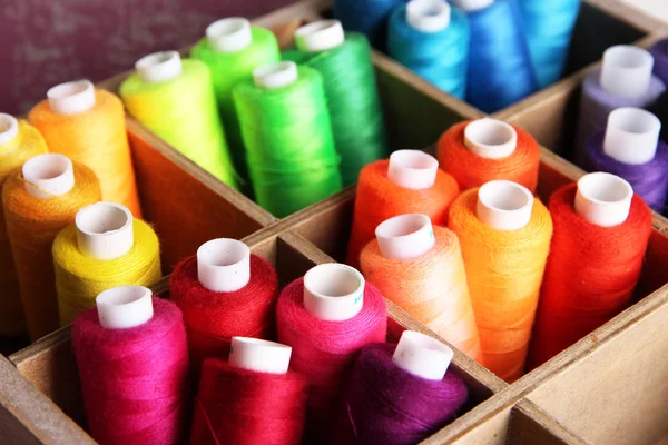 Multicolor naaien thread in houten doos, op houten achtergrond, close-up — Stockfoto