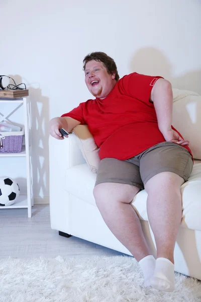 Lazy overweight male sitting on couch and watching television — Stock Photo, Image