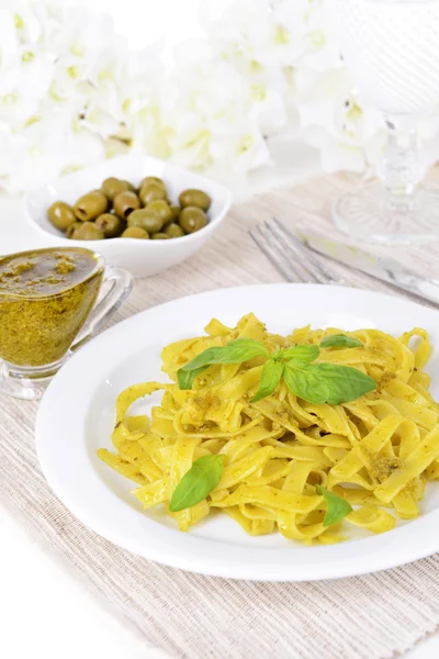 Läckra pasta med pesto på tallriken på bordet närbild — Stockfoto