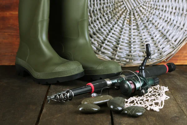 Fishing rod, gumboots and hat on wooden table close-up — Stock Photo, Image