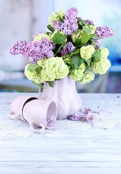 Состав с кружками чая и красивыми весенними цветами в вазе, на деревянном столе, на ярком фоне — стоковое фото