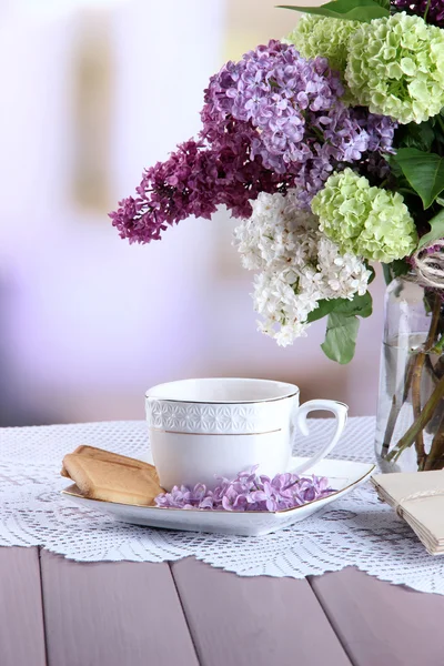 Sammansättning med kopp te, gamla brev och vacker vårblommor i vas, på träbord, på ljus bakgrund — Stockfoto