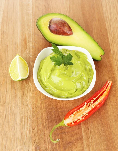 Guacamole fresco na tigela na mesa de madeira — Fotografia de Stock